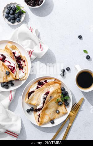 Crepes con confettura di mirtilli, ricotta e frutti di bosco freschi. Frittelle dolci per colazione. Vista dall'alto Foto Stock