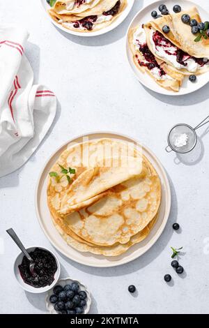 Crepes con confettura di mirtilli, ricotta e frutti di bosco freschi. Frittelle dolci per colazione. Vista dall'alto Foto Stock