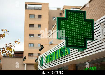 Croce verde luminosa che indica che una farmacia rimane aperta nella città di Madrid Foto Stock