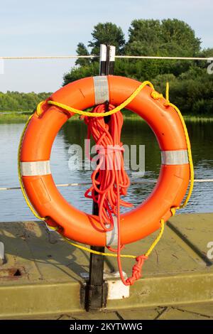 Lifebuoy sulla recinzione del molo vicino al fiume Foto Stock