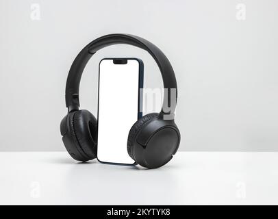 Smartphone con cuffie bluetooth con schermo bianco su sfondo neon blu, per mockup e logo Foto Stock