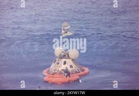 L'astronauta John L. Swigert Jr., pilota del modulo di comando, viene sollevato a bordo di un elicottero in una rete di salvataggio di elicottero Billy Pugh mentre l'astronauta James A. Lovell Jr., comandante, attende il suo turno. L'astronauta Fred W. Haise, Jr., pilota lunare, è già a bordo dell'elicottero. Nella zattera con Lovell, e in acqua, ci sono diversi nuotatori del team di demolizione subacquea della marina statunitense, che hanno assistito nelle operazioni di recupero. L'equipaggio è stato portato negli U.S.S. Iwo Jima, nave di recupero di primo livello, alcuni minuti dopo che la navicella spaziale Apollo 13 è stata spruzzata alle 12:01:44 CST il 17 aprile 1970. Foto Stock