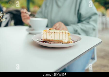 Donna mani mangiare cheesecake mentre fare colazione in caffè all'aperto, tempo libero, cibo e bevande, persone e concetto di stile di vita Foto Stock