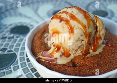 Primo piano appetitoso Texture di cookie caldo condito con gelato e salsa al caramello salata Foto Stock