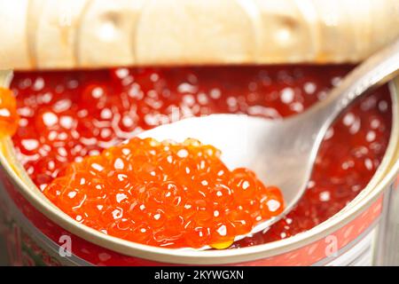 Lattina di metallo e cucchiaio con delizioso caviale rosso Foto Stock