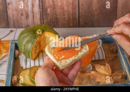 donna che sparge marmellata di zucca fatta in casa su un pezzo di pane tostato Foto Stock