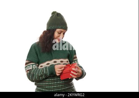 Affascinante donna multi-etnica in Xmas pattered green maglione, scompatta regalo di Natale, su sfondo bianco. Copia spazio pubblicitario Foto Stock