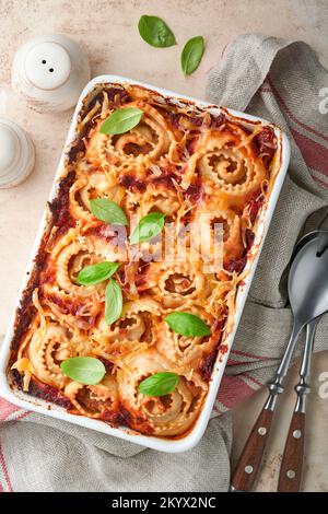 Lasagne. Lasagne fatte in casa - rotolo di pasta con salsa di pomodoro, crema di formaggio e basilico su padella bianca su fondo di ardesia leggera, pietra o cemento. IO Foto Stock