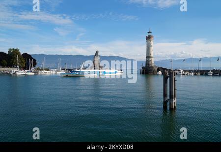 Il bellissimo porto soleggiato dell'isola di Lindau con faro e la scultura del Leone bavarese sul lago Costanza (Bodensee) con le Alpi Foto Stock