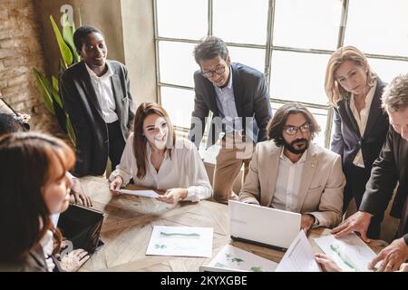 Gruppo di imprenditori multietnici che operano in un'energia rinnovabile analizzano i dati sull'energia elettrica. Foto Stock