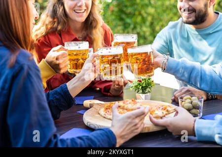 Primo piano di amici seduti al pub bere birra e divertirsi Foto Stock