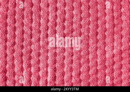 La tessitura del tessuto lavorato a maglia. Primo piano di una coperta a maglia. Dimostrazione dei colori di 2023 - Viva Magenta. Foto Stock