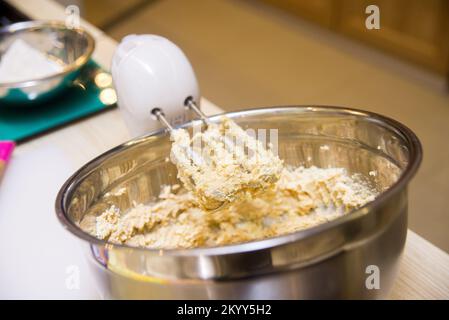 il mixer elettrico consente di impastare l'impasto in un recipiente di metallo profondo Foto Stock