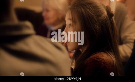 Primo piano di una giovane ragazza asiatica. Mangia e beve succo. La famiglia festeggia Natale, Capodanno o il giorno del Ringraziamento. Tavolo per le vacanze servito. Calda atmosfera di famiglia cena di Natale a casa. Foto Stock