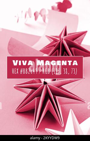 Viva Magenta colore dell'anno 2023. Vibranti stelle di carta origami, decorazioni natalizie fai da te fatte a mano. Stelle autogestiti di Natale realizzate con carta riciclata. Foto Stock