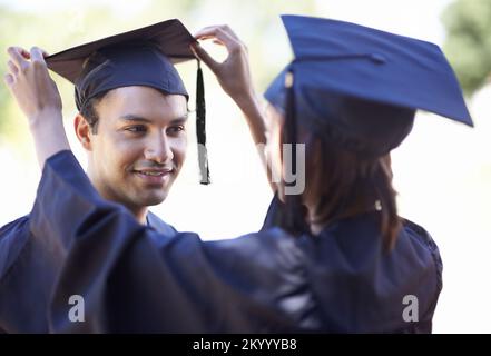 Ex compagni di classe che si guardano l'un l'altro. Una donna laureata che fissa il suo cappello di boyfriends. Foto Stock