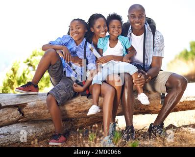 Amano una buona escursione insieme. Ritratto di una famiglia felice-guardando seduto su un log mentre fuori su un'escursione insieme. Foto Stock