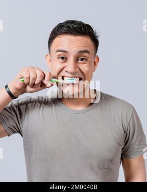 Volto di bell'uomo che gli sfiorava i denti. Concetto di pulizia e cura dei denti. Faccia del ragazzo spazzolando i denti isolati. Concetto di sorriso orale e dentale, sorridente Foto Stock