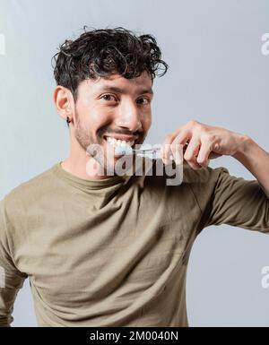 Sorridendo l'uomo spazzolando i denti isolati, il volto dell'uomo bello spazzolando i denti. Concetto di pulizia e cura dei denti. Faccia del ragazzo spazzolando i denti isolati Foto Stock