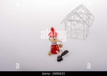Pinocchio è seduto accanto a un modello di casa Foto Stock