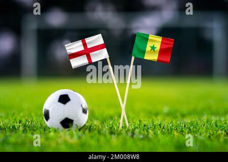 Inghilterra - Senegal. Otto finale, ultima partita di calcio 16. Bandiere nazionali fatte a mano e palla da calcio su erba verde. Stadio di calcio sullo sfondo. Nero Foto Stock
