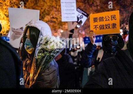 Boston, Stati Uniti. 02nd Dec, 2022. Un dimostratore tiene fiori durante una veglia per le tragiche vittime del fuoco di Urumqi al Memoriale di Tiananmen. Oltre 400 persone partecipano a una veglia a lume di candela al Tiananmen Memorial a Boston Chinatown per protestare contro la politica cinese di zero-covid e per commemorare le vittime del tragico incendio di Urumqi il 2 dicembre 2022. (Foto di Tang Ka Huen/SOPA Images/Sipa USA) Credit: Sipa USA/Alamy Live News Foto Stock