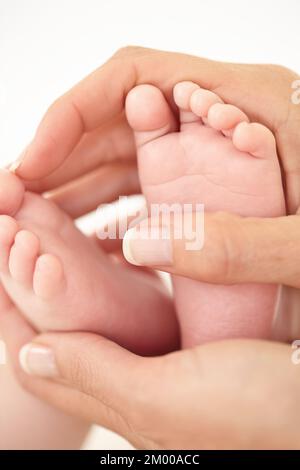 Base di piedini piccoli. Primo piano ritagliato di una madre che tiene i piedi dei suoi bambini. Foto Stock