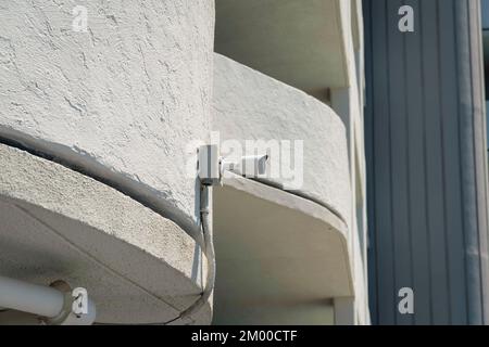 Primo piano di una TVCC montata a parete a Destin, Florida. Vista della telecamera di sorveglianza in una vista ad angolo basso montata su una parete bianca ricurva dipinta di un edificio. Foto Stock