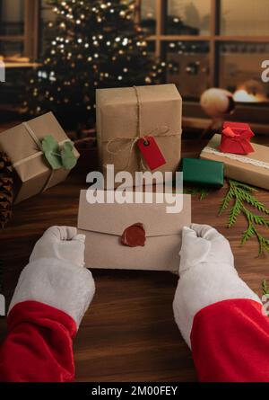 babbo natale che regge un'elegante busta su un intimo sfondo defocused casa Foto Stock