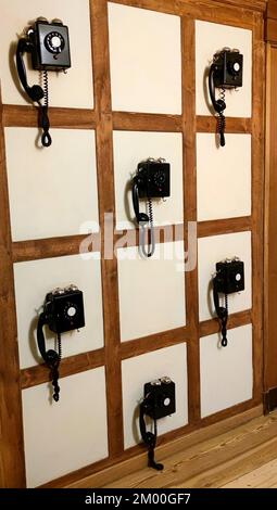 Vista divertente di alcuni telefoni analogici antichi su una parete. Foto Stock