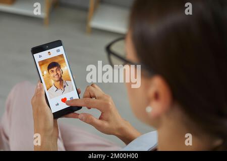 Primo piano del telefono cellulare con l'applicazione aperta datazione nelle mani di donna in cerca di rapporto. Foto Stock