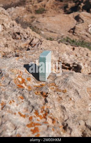 Saponetta shampoo al sale marino blu sulla spiaggia in una roccia naturale in vista verticale Foto Stock