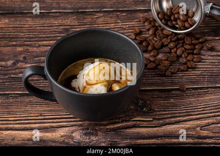 Espresso con gelato in tazza di porcellana nera su tavolo di legno. Caffè affogato Foto Stock