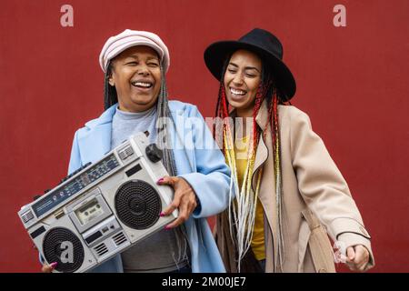 Madre africana felice con la figlia che ha ballare e ascoltare musica con stereo boombox vintage Foto Stock