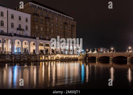 Amburgo, Germania - 11 27 2022: Colpo notturno dell'alsterarkaden di amburgo con la flotta dell'alsterco davanti ad esso Foto Stock