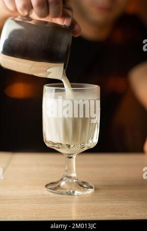 Barista versando latte al vapore in una tazzina di caffè, creando un bellissimo latte. Caffè, estrazione, profondità, tazza, arte, concetto di barista. Spazio di copia Foto Stock