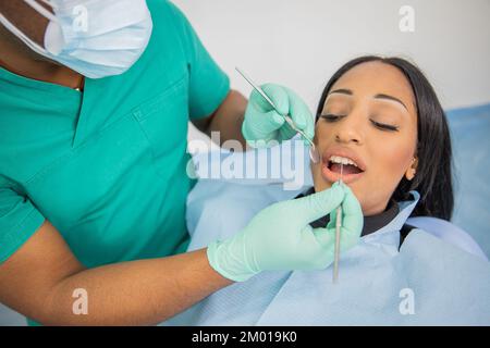 Ragazza durante una visita dentale, medico con strumenti dentali esamina la sua bocca Foto Stock