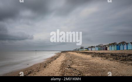 Capanne sulla spiaggia di Mersea Island in Essex. Moody, cielo nuvoloso e foto a lunga esposizione. Foto Stock