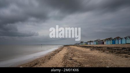 Capanne sulla spiaggia di Mersea Island in Essex. Moody, cielo nuvoloso e foto a lunga esposizione. Foto Stock