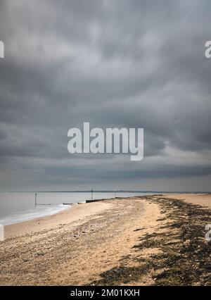 Spiaggia di Mersea Island in una nuvolosa giornata invernale. Esposizione lunga, foto moody. Foto Stock