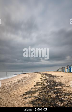 Capanne sulla spiaggia di Mersea Island in Essex. Moody, cielo nuvoloso e foto a lunga esposizione. Foto Stock