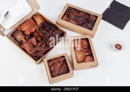Spuntino a base di carne di manzo con un alto contenuto proteico e carne magra. cibo affumicato e secco. sfondo bianco, spazio di copia. Foto di alta qualità Foto Stock