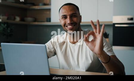 African Latina uomo maschio in cucina a casa giocare online browser gioco in rete scommessa lavoro remoto con laptop shopping in Internet store ordine di consegna Foto Stock