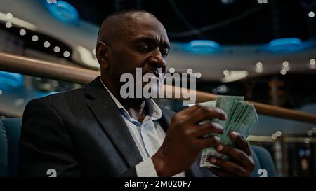 Pensivo pensando afro-americano imprenditore imprenditore uomo ricco datore di lavoro conteggio denaro denaro denaro dollari risparmio bilancio in casa Foto Stock