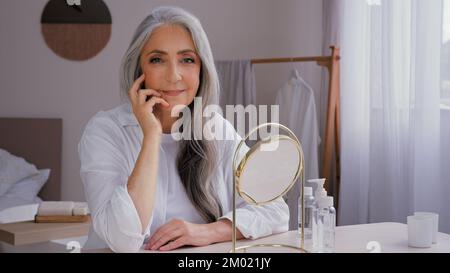 Vecchia caucasica bella 60s signora anziana anziana anziana anziana anziana anziana modello donna con capelli grigi femmina nonna nonna nonna nonna che guarda la macchina fotografica seduta a casa Foto Stock
