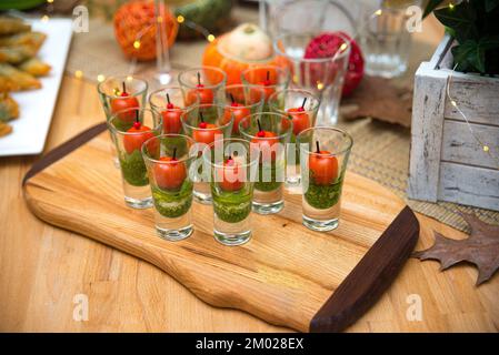 Tanti shot di tartine caprese con pesto, mini pomodori ciliegini e palline di mozzarella. Una tavola di antipasti. Foto Stock