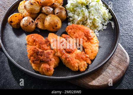 Cotolette di pollo impanate servite con patate e cavolo. Foto Stock