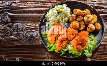 Cotolette di pollo impanate servite con patate e cavolo. Foto Stock