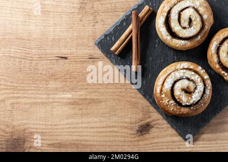 Panini alla cannella su tavolo di legno. Dessert svedese Kanelbule Foto Stock