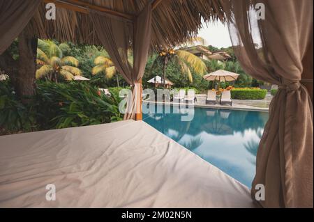 Lettino vuoto accanto alla piscina sullo sfondo del resort Foto Stock